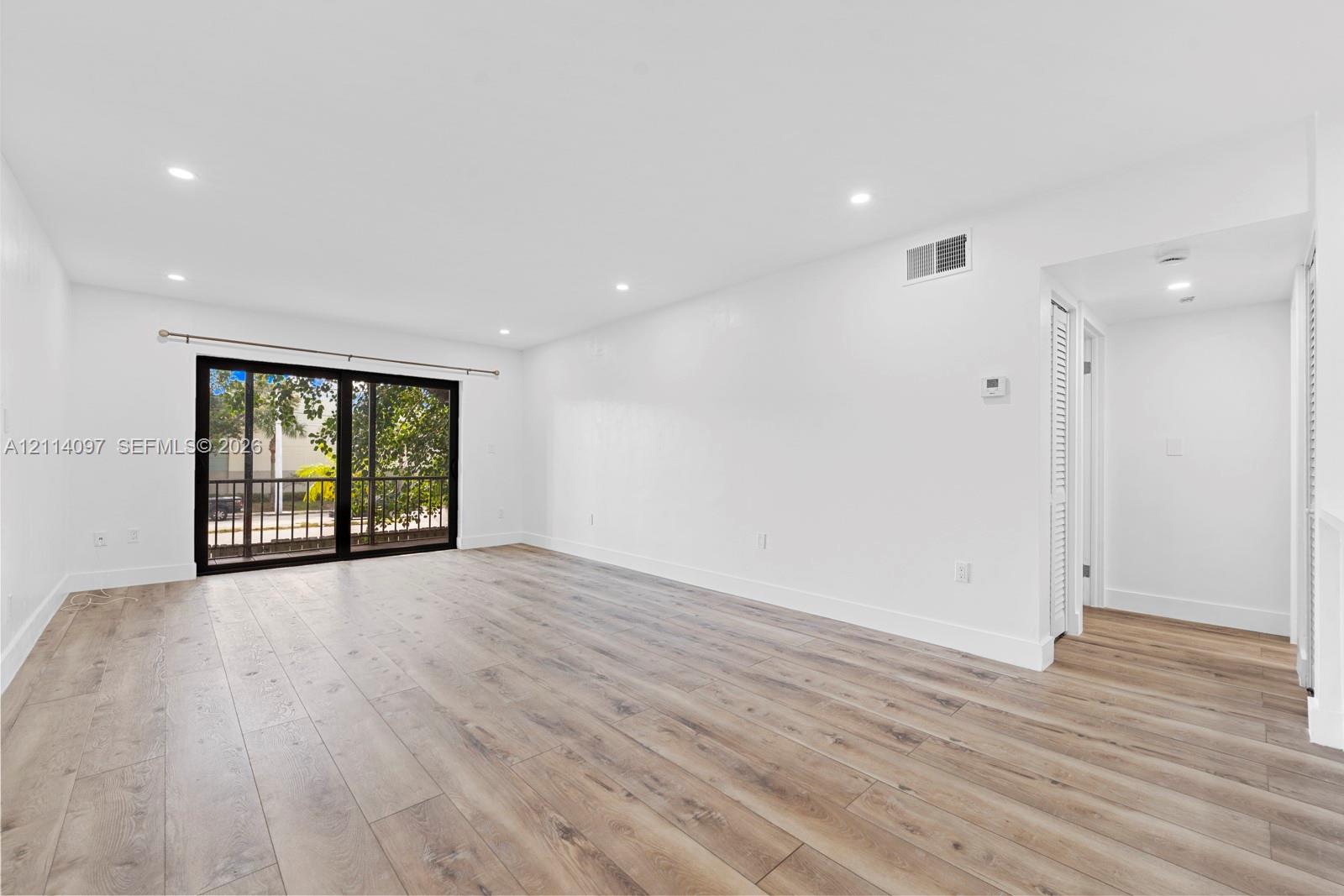 Open interior featuring wood-finish flooring, recessed lighting, and large sliding glass doors with black framing
