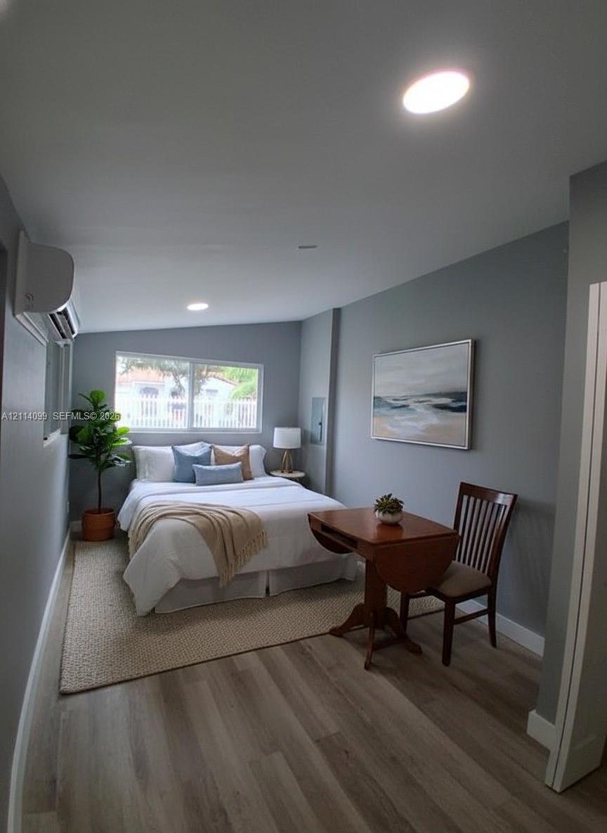 Wood-finish flooring, recessed lighting, wall-mounted climate control unit, and a horizontal sliding window