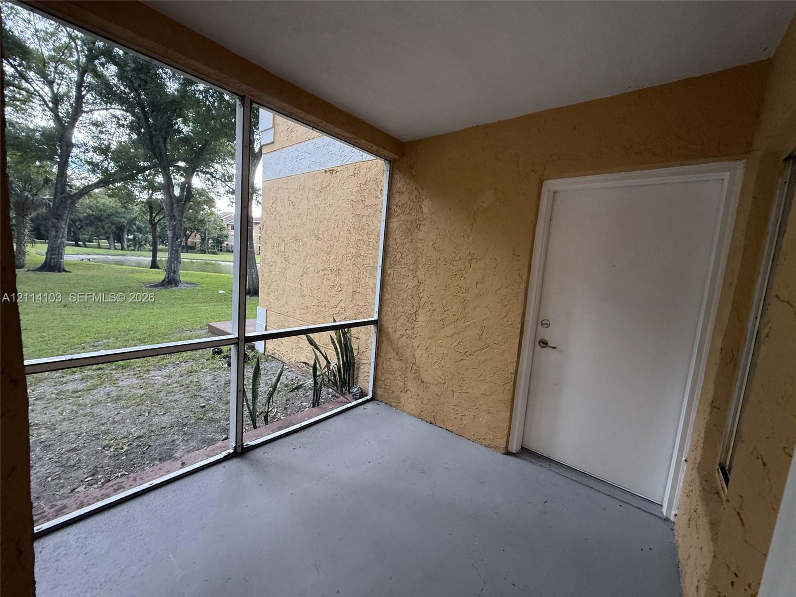 Screened-in porch featuring a painted concrete floor, textured stucco walls, and a secure exterior entry door