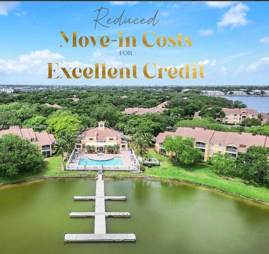 Waterfront multi-building residential complex featuring a community swimming pool, paver deck, and private T-shaped boat dock