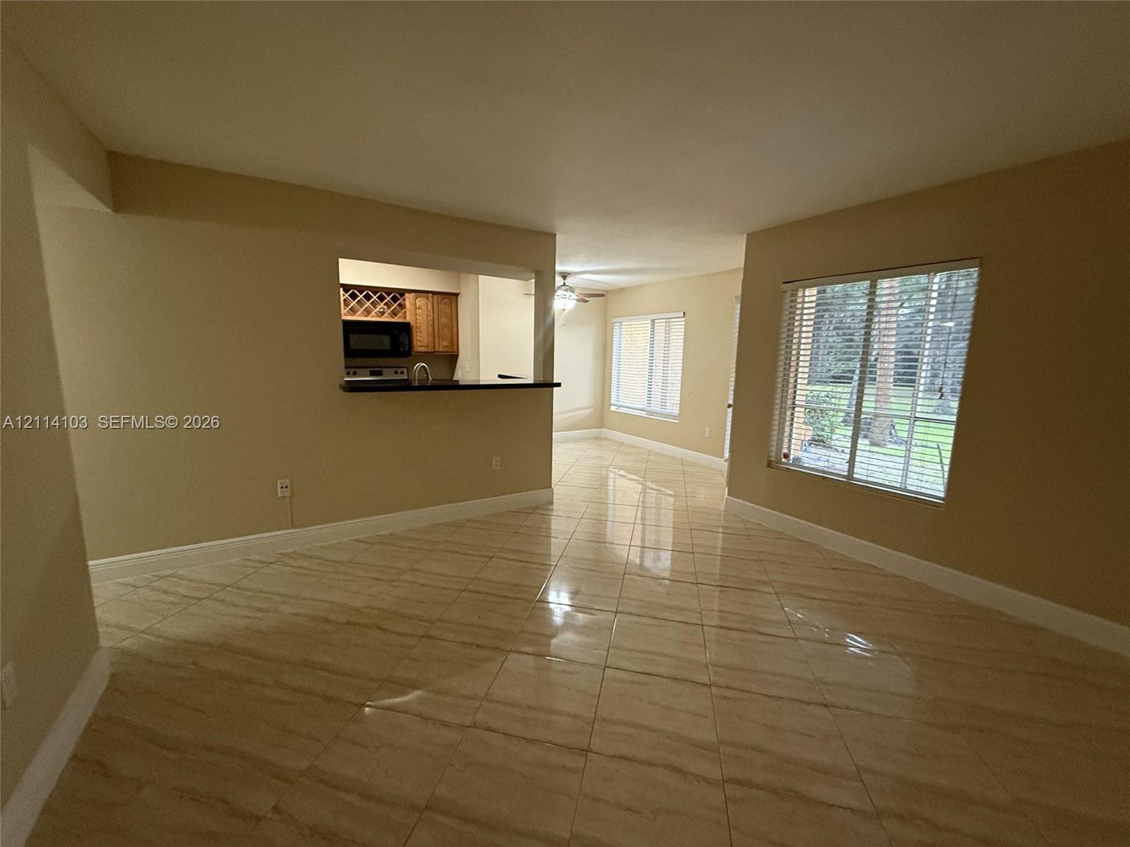 Tile flooring, pass-through opening to kitchen, built-in wine rack, and large windows with horizontal blinds