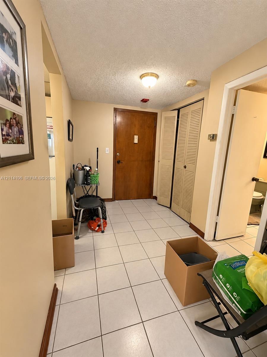Entryway featuring ceramic tile flooring, solid wood-finish entry door, and bi-fold closet doors with louvered panels