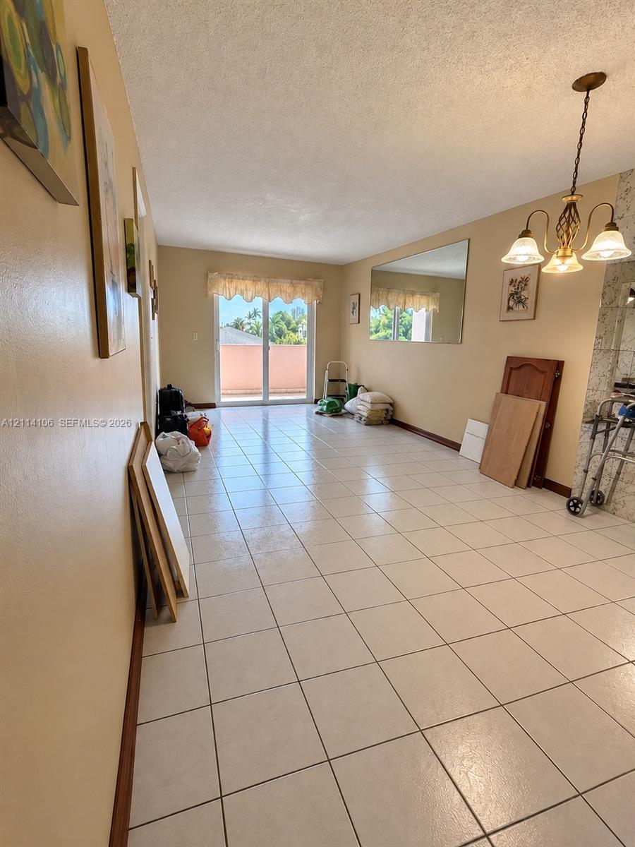 Tile flooring, multi-light hanging chandelier, wall-mounted mirror, and sliding glass door