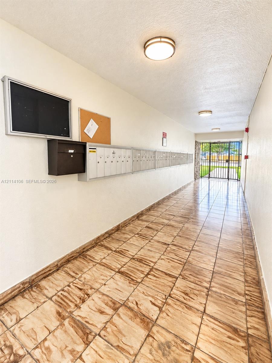 Hallway featuring ceramic tile flooring, built-in metal mailboxes, and flush-mount ceiling lighting