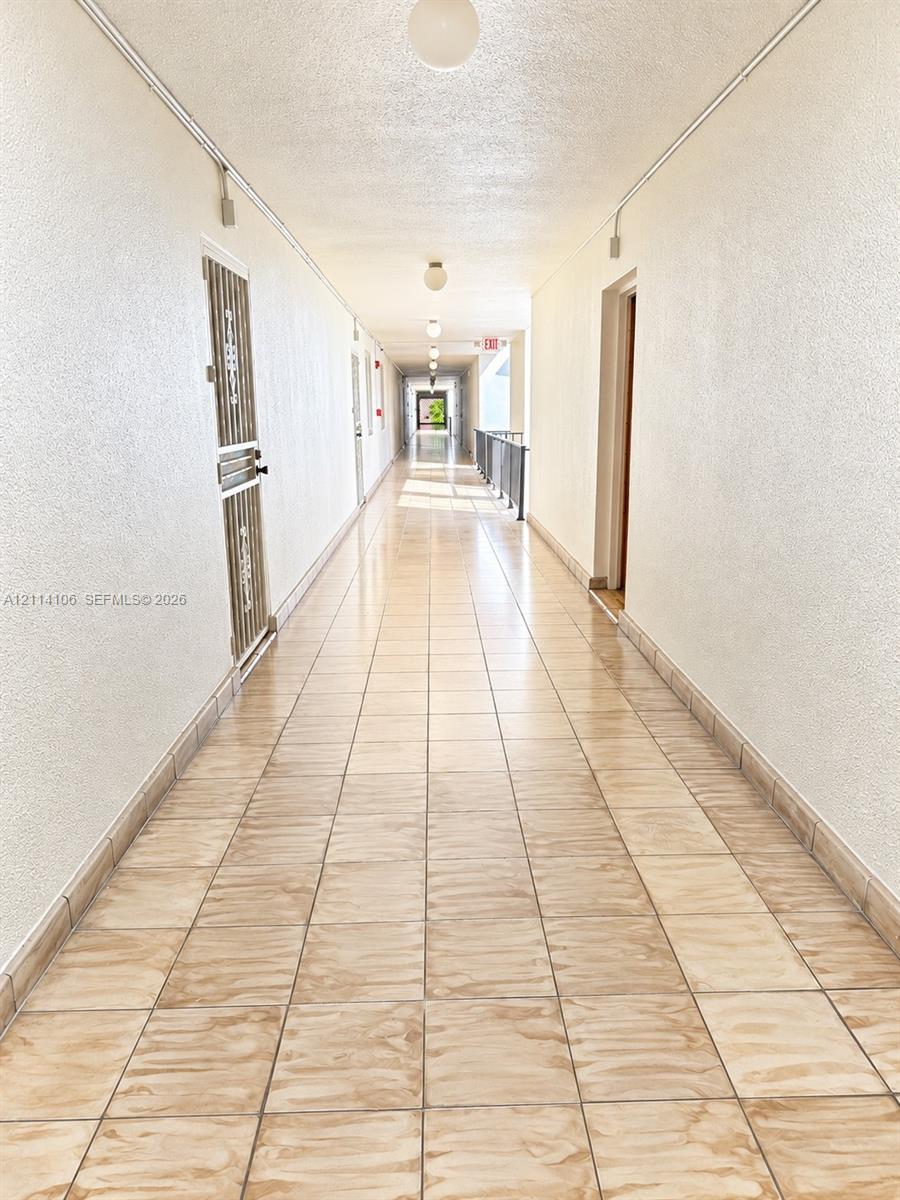 Hallway featuring ceramic tile flooring, textured wall finishes, and flush-mount ceiling lighting