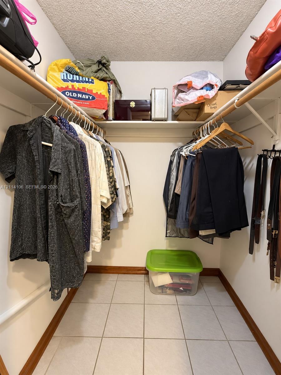 Walk-in closet featuring tiled flooring, built-in shelving, and dual-level hanging rods