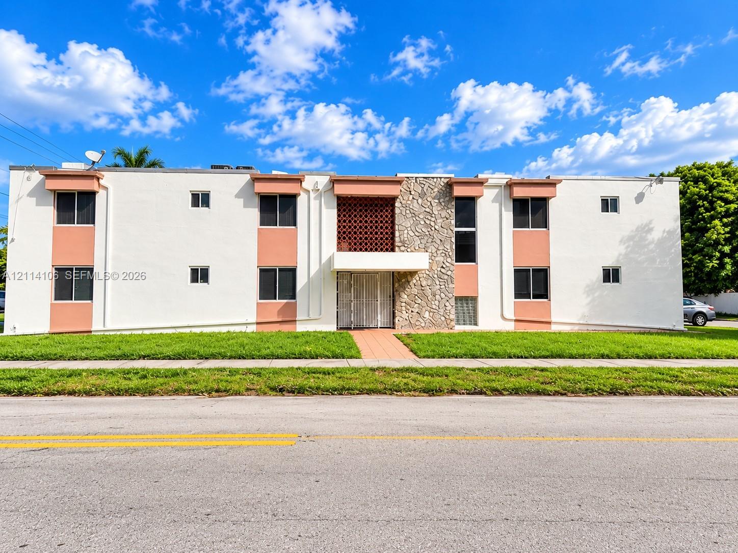 Two-story exterior featuring a light-toned stucco faade, stone veneer accents, decorative geometric masonry screens, and prominent rectangular window configurations