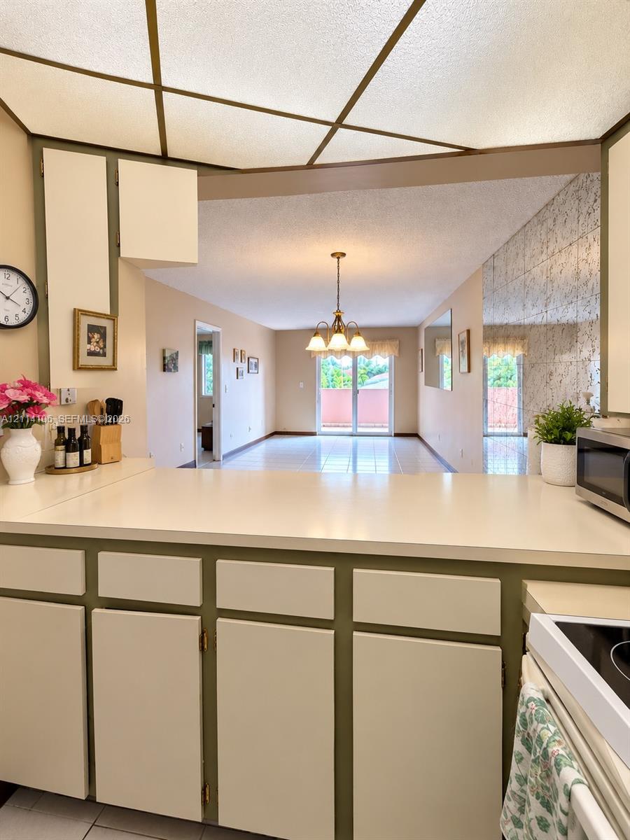 Kitchen featuring solid-surface countertops, custom cabinetry with integrated hardware, and a drop-panel ceiling with decorative framing