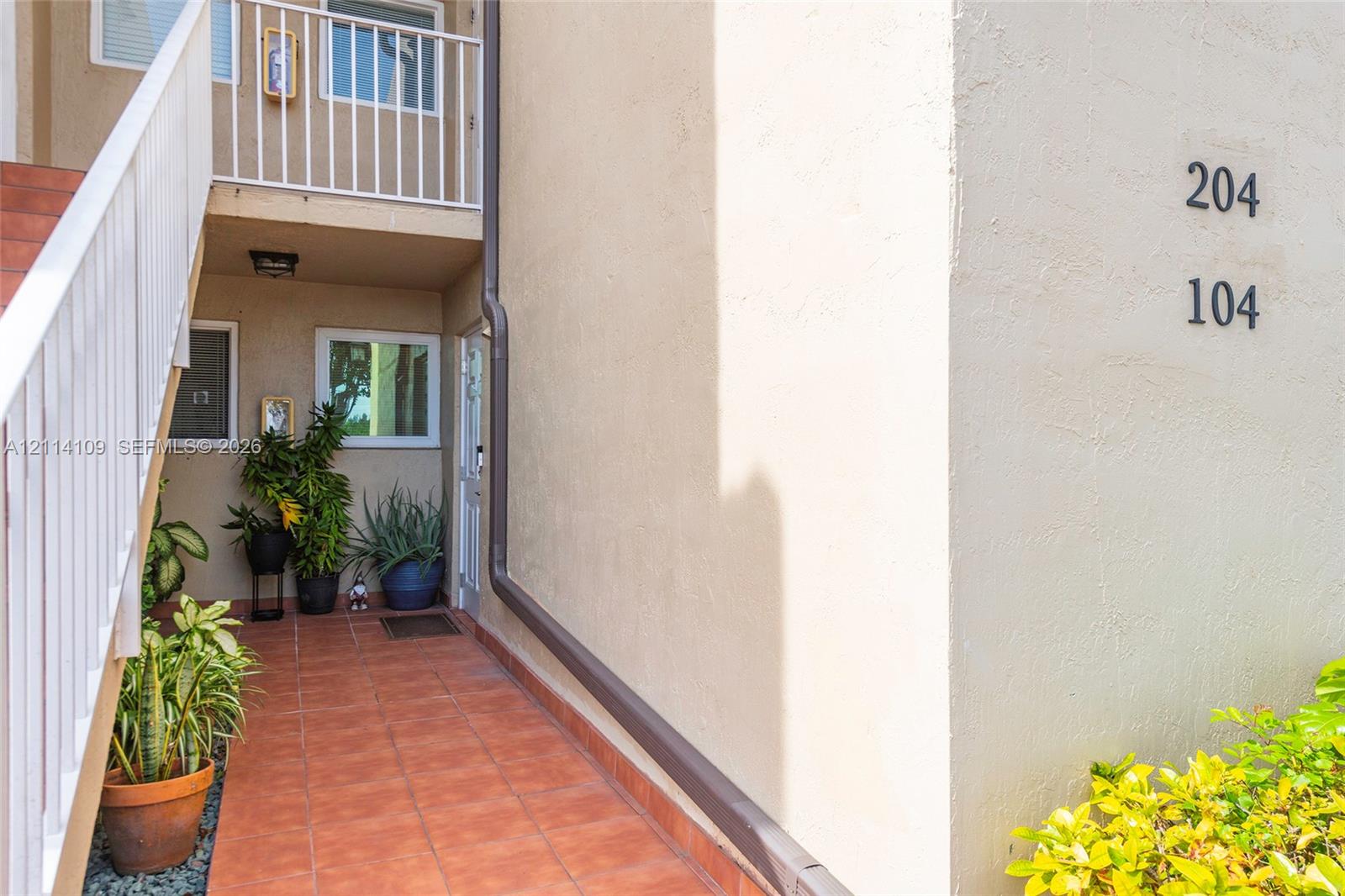Stucco exterior featuring terracotta-style tile flooring, white metal staircase railings, and integrated external lighting fixtures
