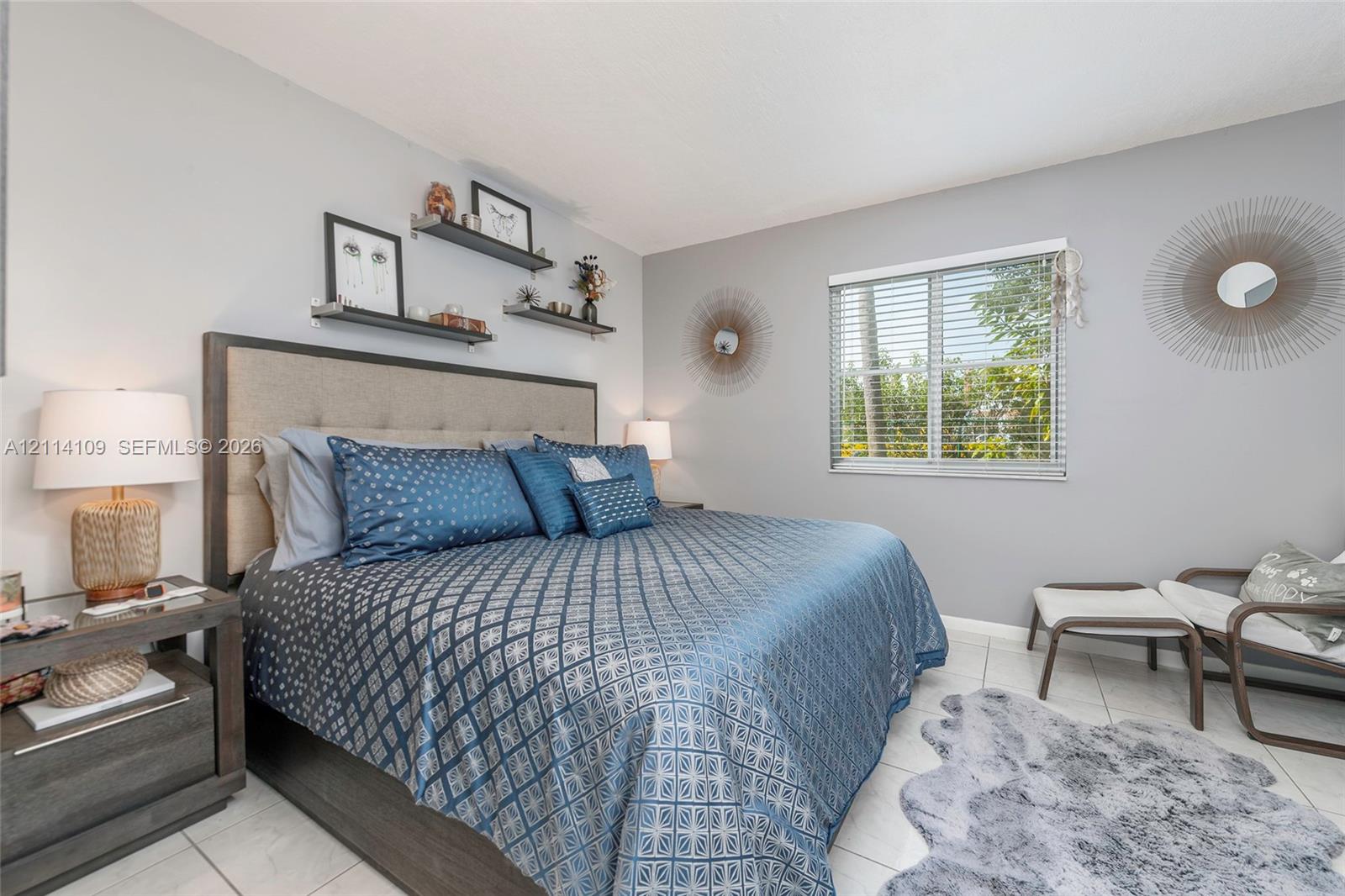 Bedroom featuring neutral wall paint, tile flooring, and a sliding window with horizontal blinds