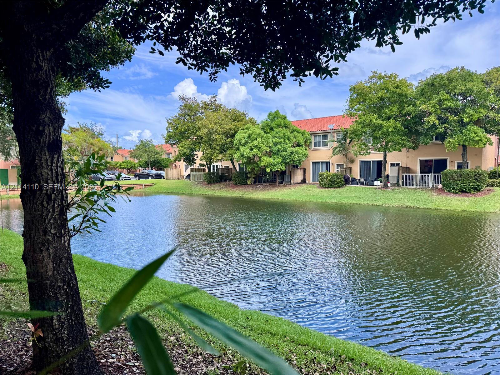 Waterfront exterior featuring a concrete tile roof, manicured lawn, and mature landscaping