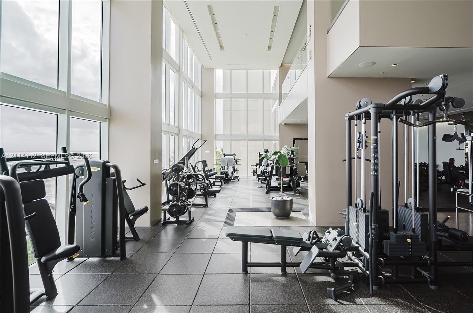 Fitness center featuring floor-to-ceiling windows, high ceilings, recessed lighting, and large-format tile flooring