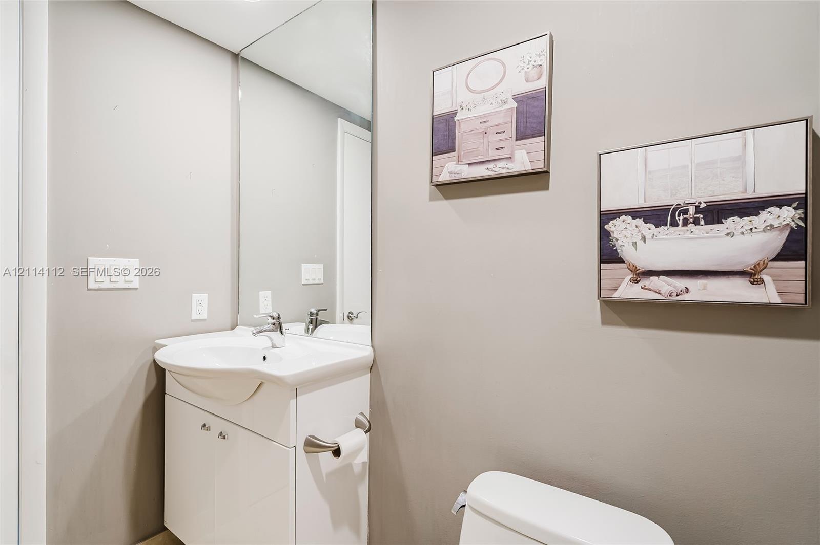 White vanity with an integrated basin, high-gloss countertop, and wall-to-wall mirror