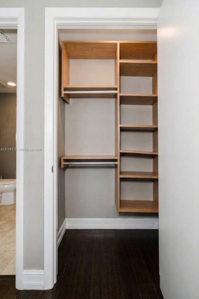Built-in closet featuring light wood-finish shelving, multiple storage compartments, and integrated hanging rods