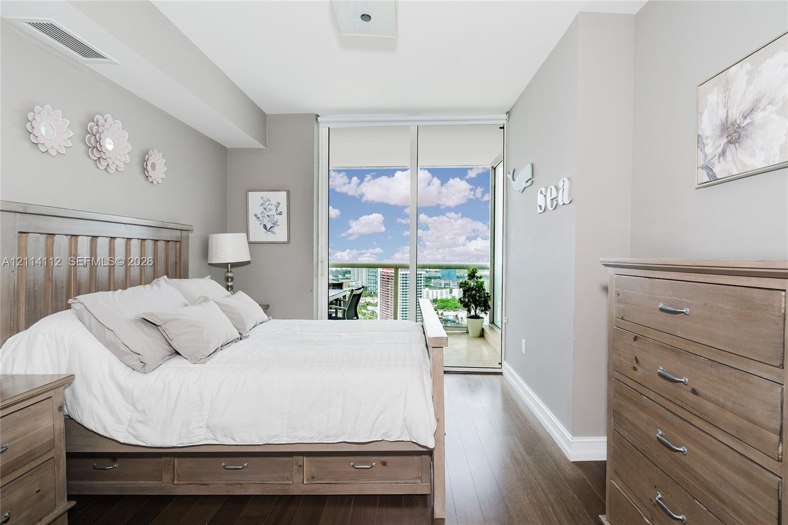 Wood-finish flooring, full-height sliding glass doors, and a private balcony