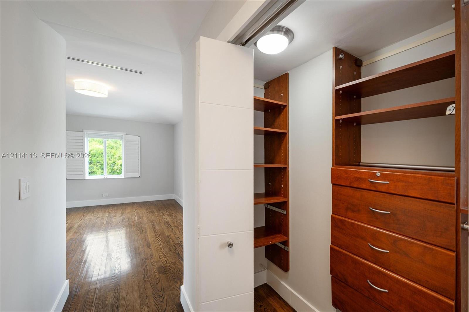 Custom storage system with wood-finish shelving and built-in drawers, polished metal hardware, and wood-finish flooring