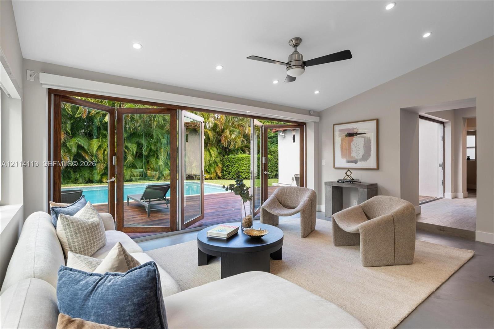 Multi-panel folding glass doors, recessed lighting, ceiling fan, neutral wall palette, and polished concrete flooring