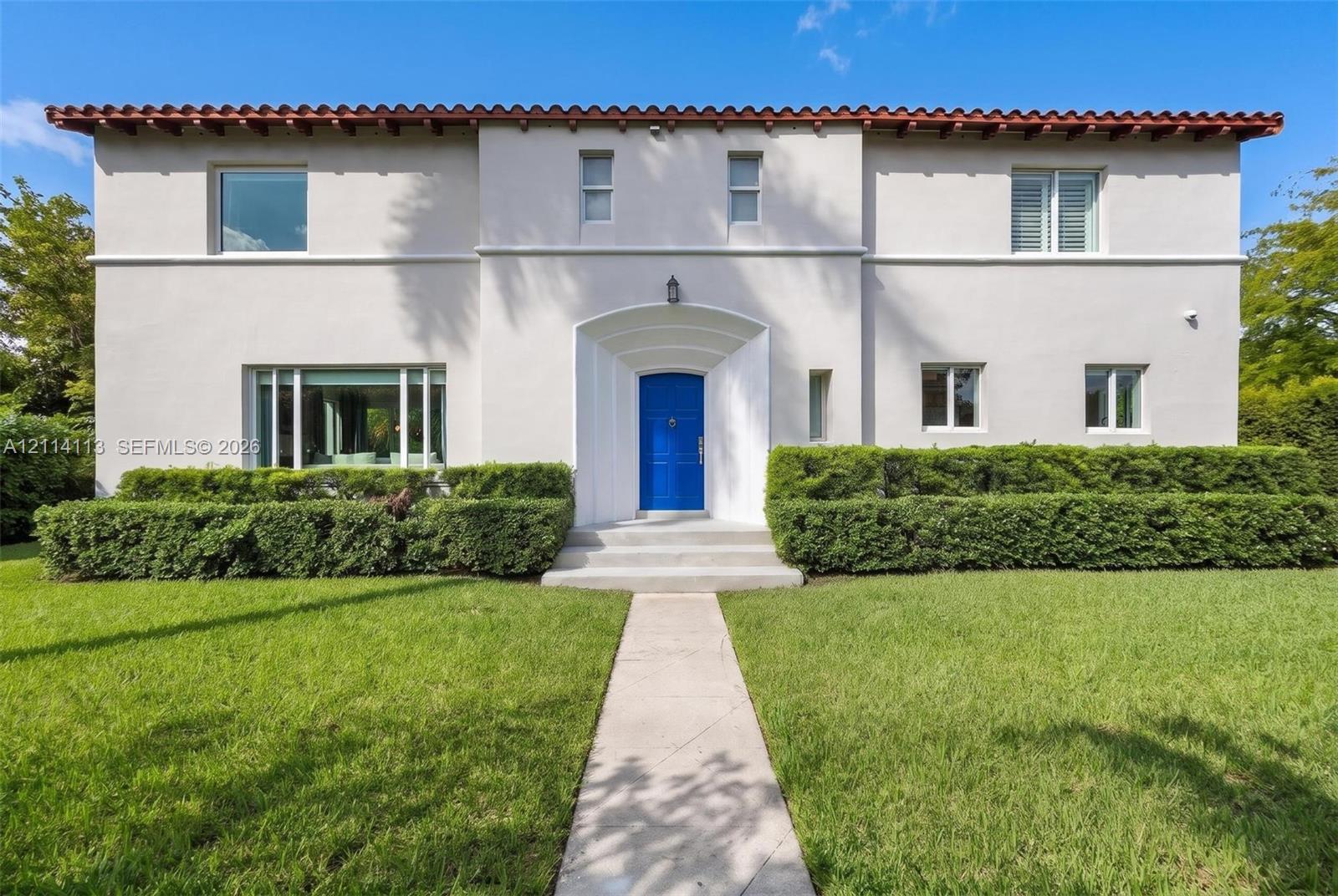 Art Deco facade, red tile roof, recessed arched entryway, and multi-paned windows