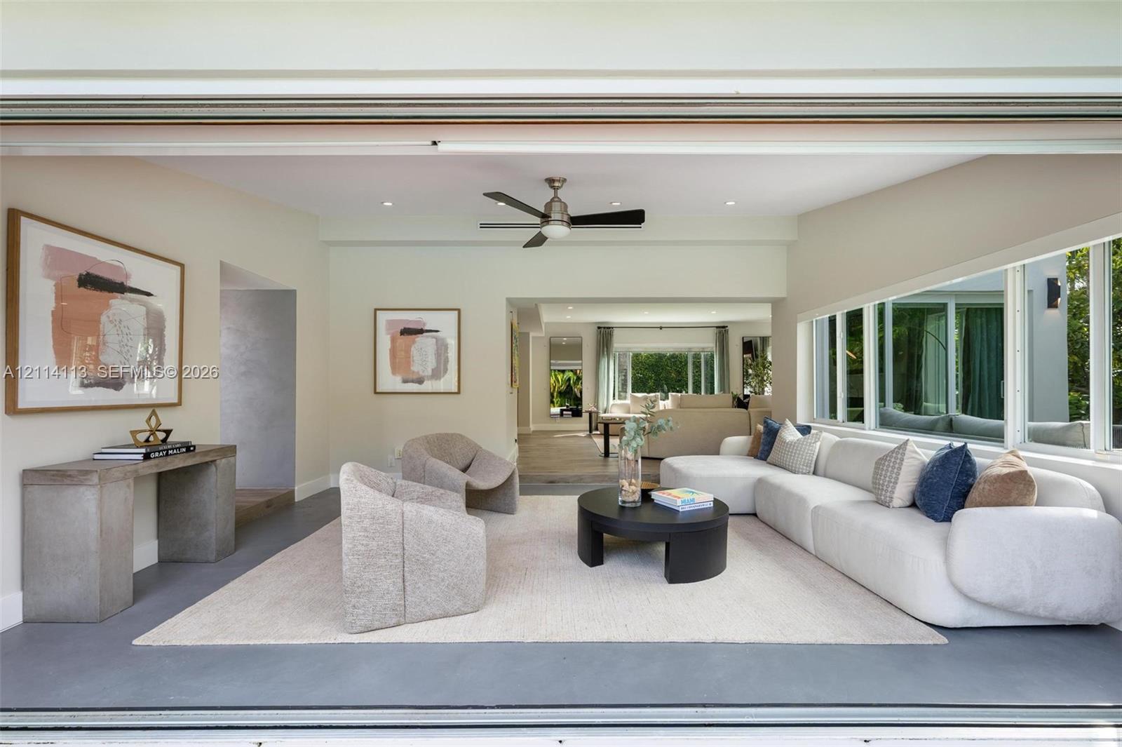 Open-concept interior featuring large-format retractable glass walls, recessed lighting, ceiling fan, and painted walls