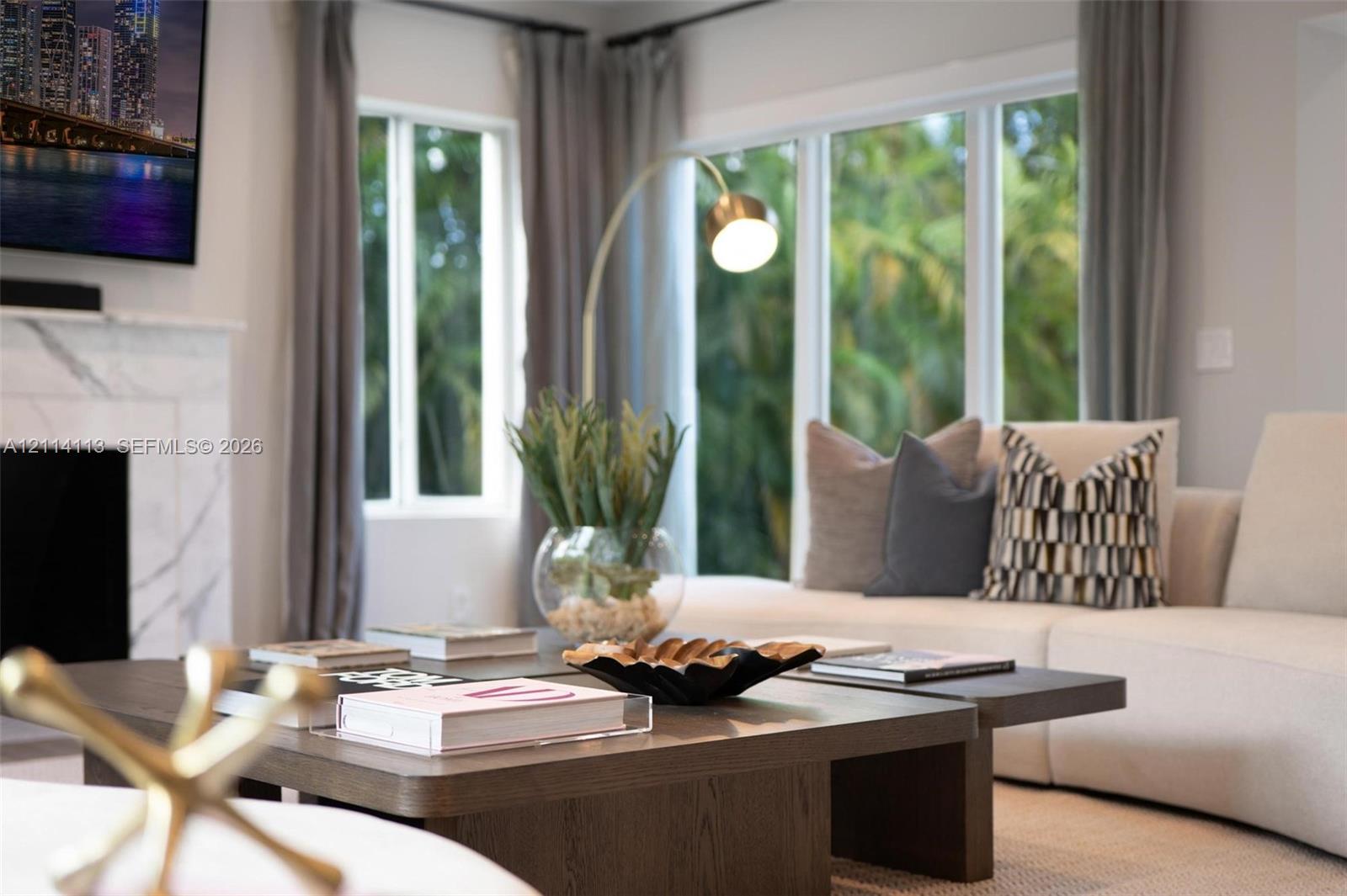 Living area featuring a floor-to-ceiling stone-surround fireplace, large windows, and neutral wall tones