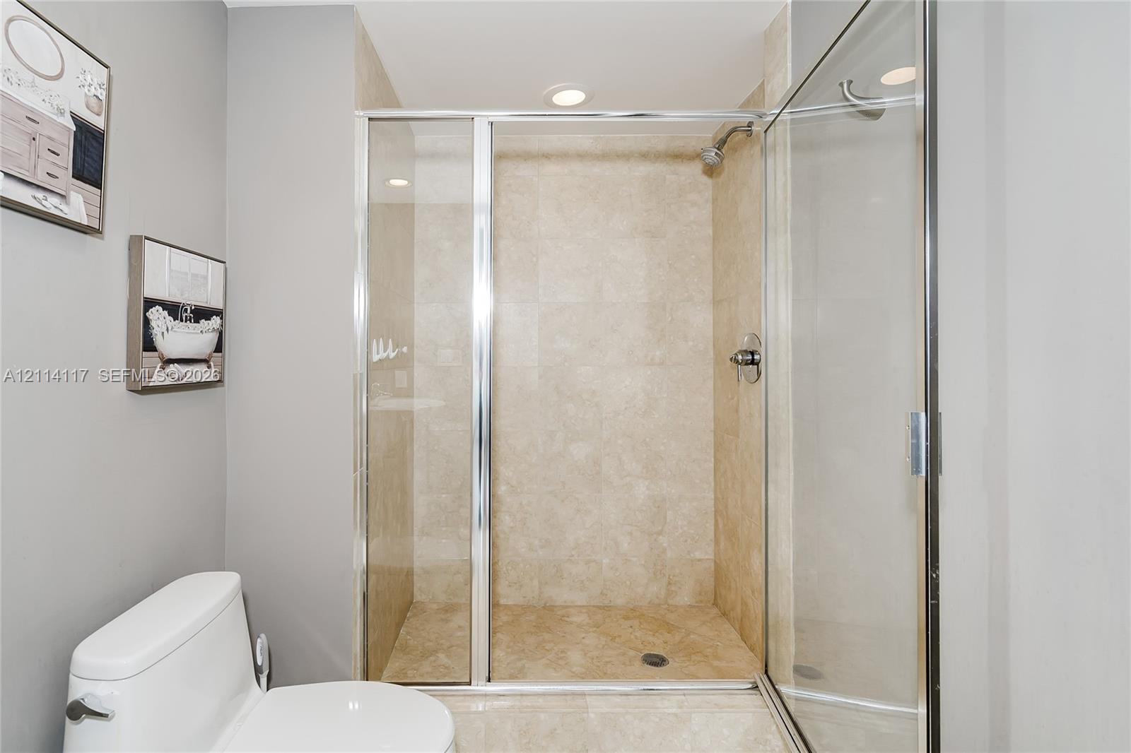 Walk-in shower featuring tile surrounds, chrome fixtures, and a glass enclosure, complemented by a white porcelain toilet