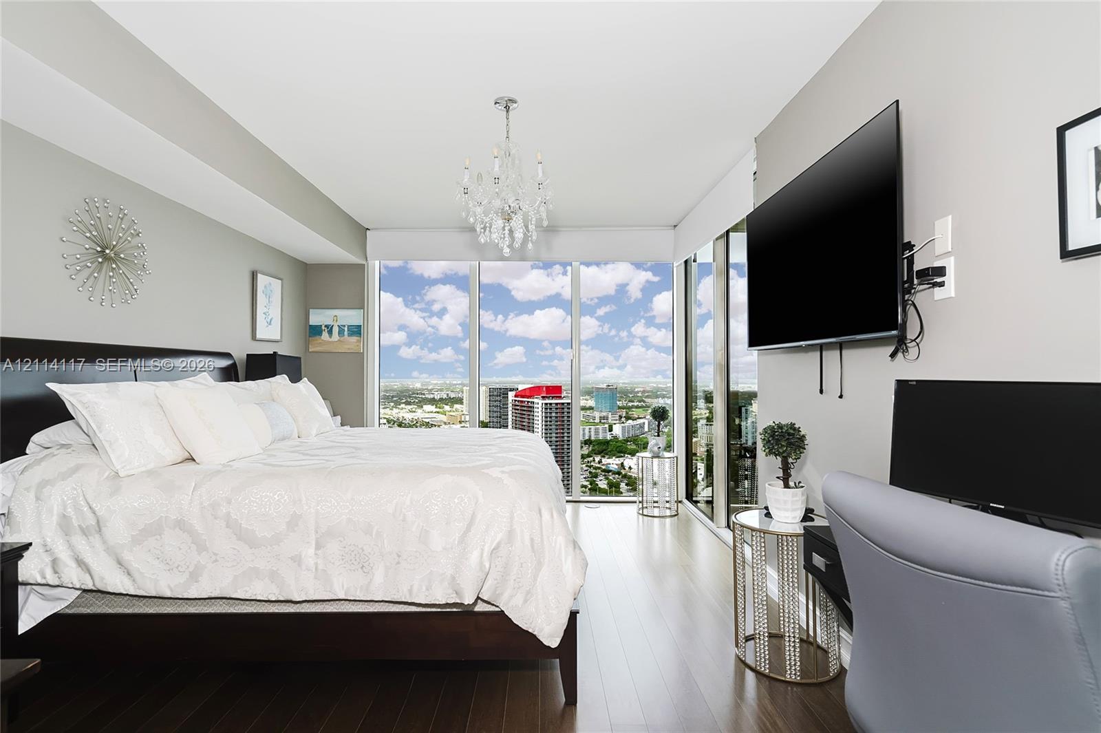 Floor-to-ceiling windows, wood-finish flooring, and a crystal chandelier
