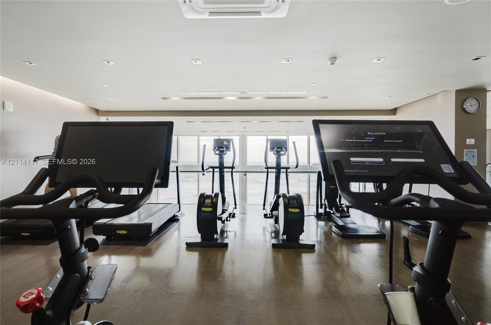 Fitness center featuring wood-finish flooring, recessed lighting, and large windows with integrated handrails