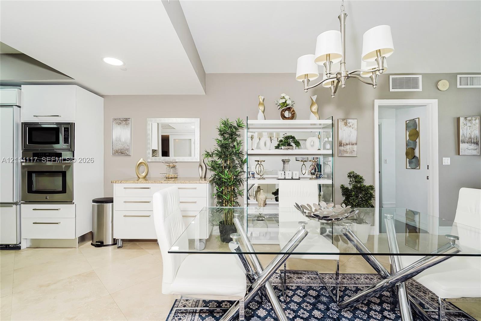 Dining area featuring large-format tile flooring, a multi-arm chandelier with white fabric shades, and built-in cabinetry with stone-surface countertops