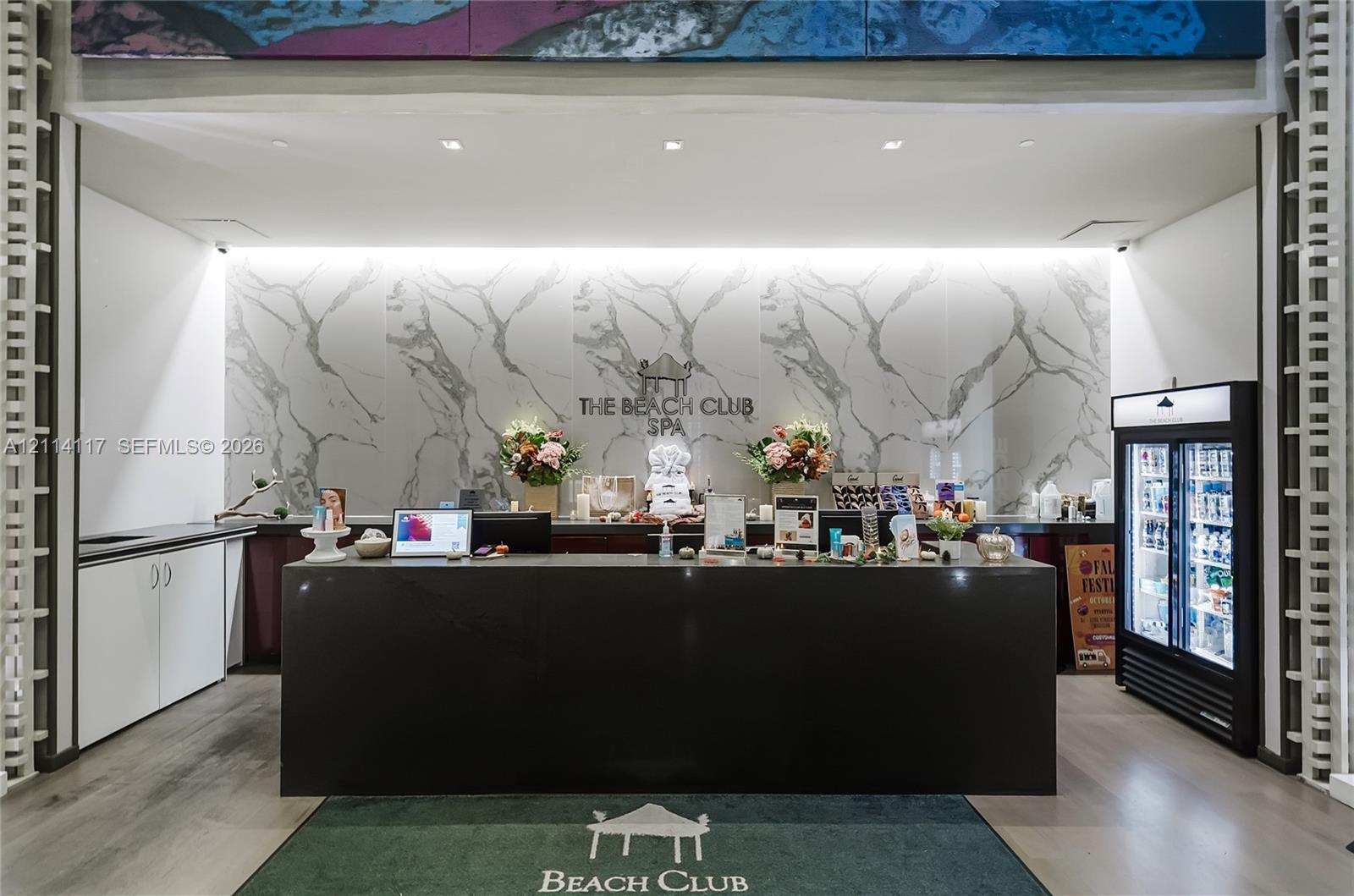 Reception area featuring a dark stone-finish service counter, large-format veined stone wall cladding, white built-in cabinetry, and wood-finish flooring