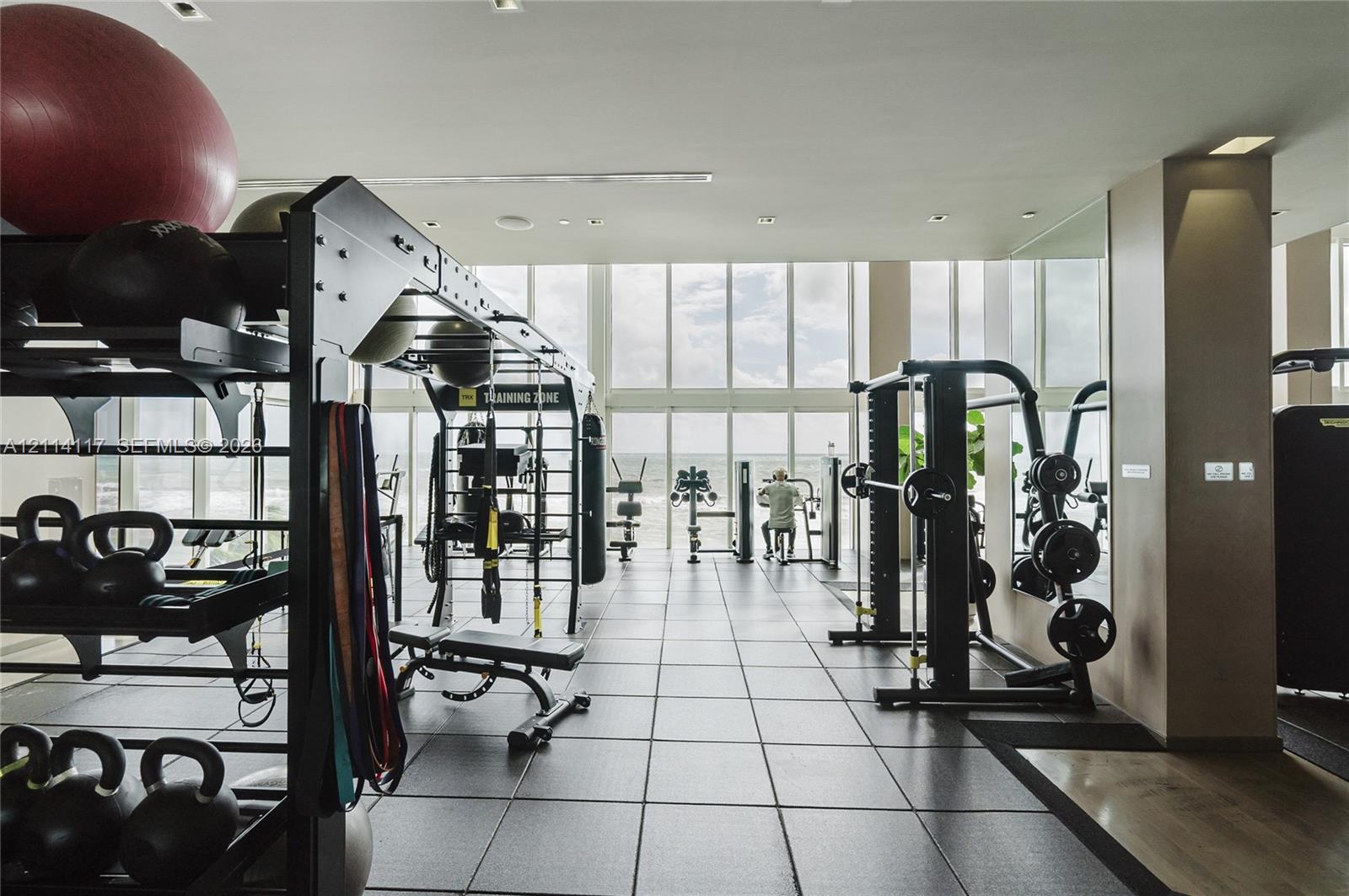 Fitness facility featuring floor-to-ceiling windows, high ceilings with recessed lighting, and large-format tile flooring