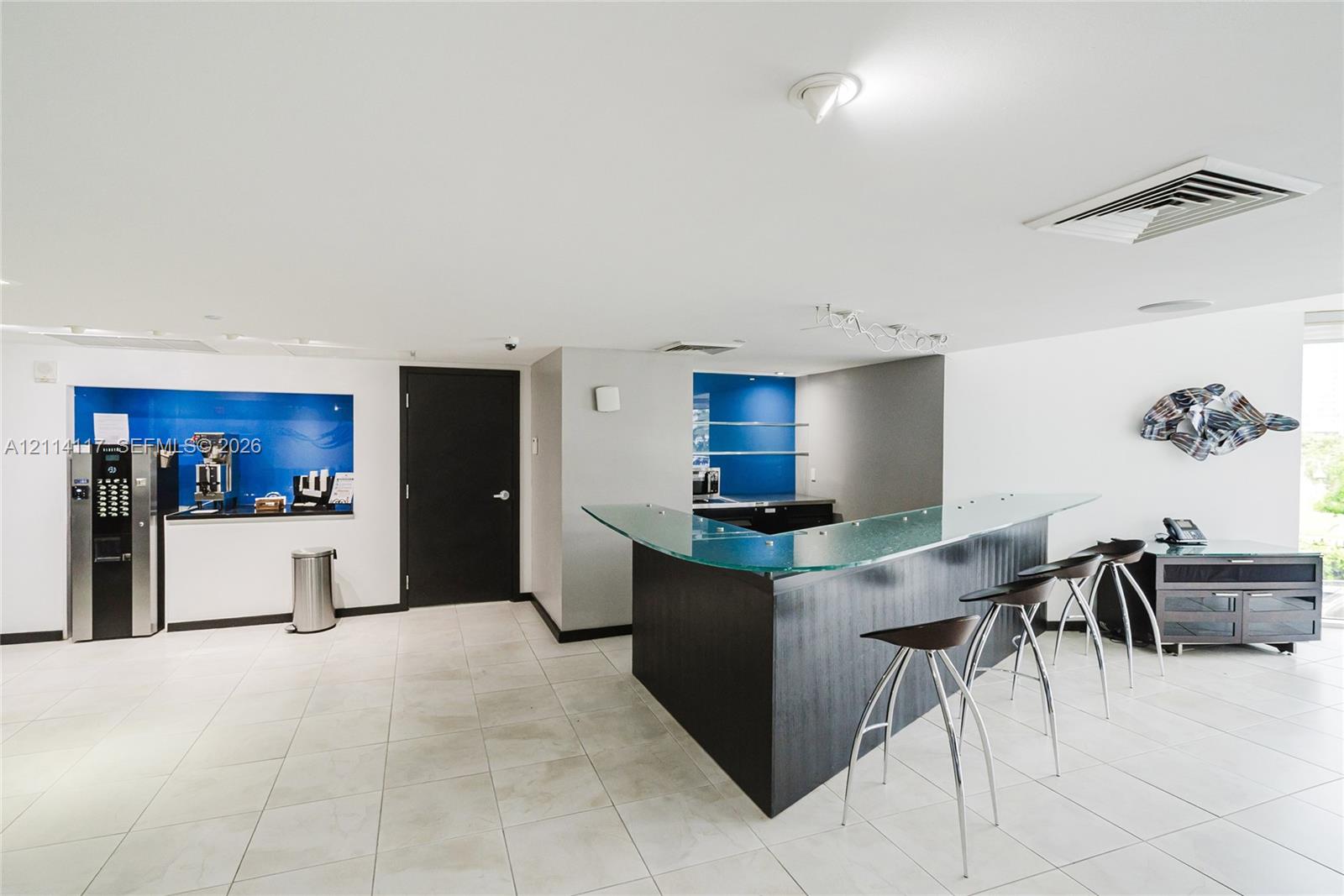 Custom wet bar featuring a glass countertop, dark wood-finish cabinetry, tile flooring, and integrated blue glass backsplashes