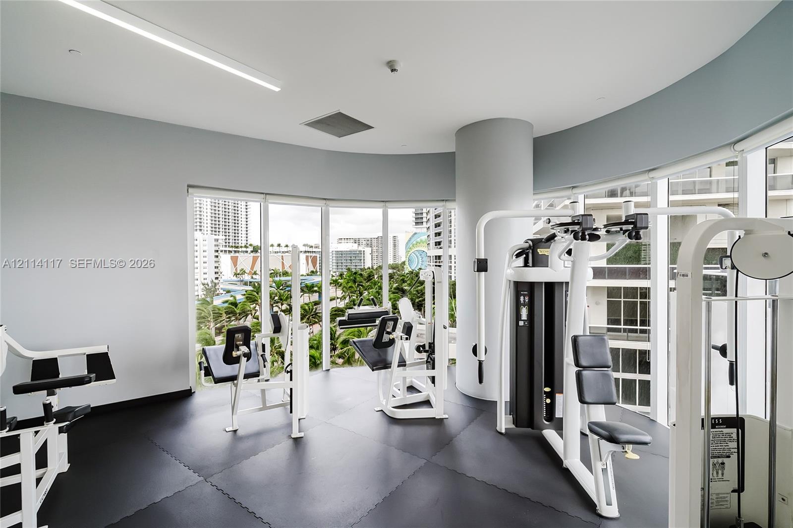 Fitness center featuring floor-to-ceiling windows, curved walls, and impact-resistant modular rubber flooring