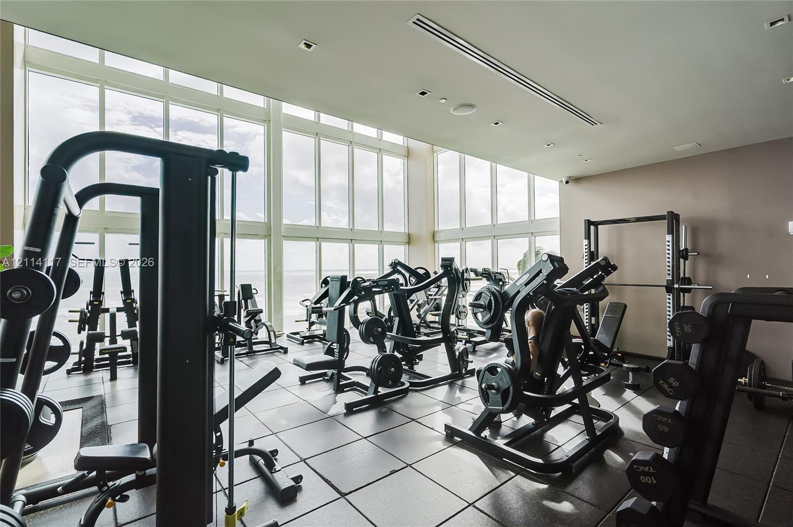 Fitness center featuring floor-to-ceiling windows, natural lighting, and modular tile flooring