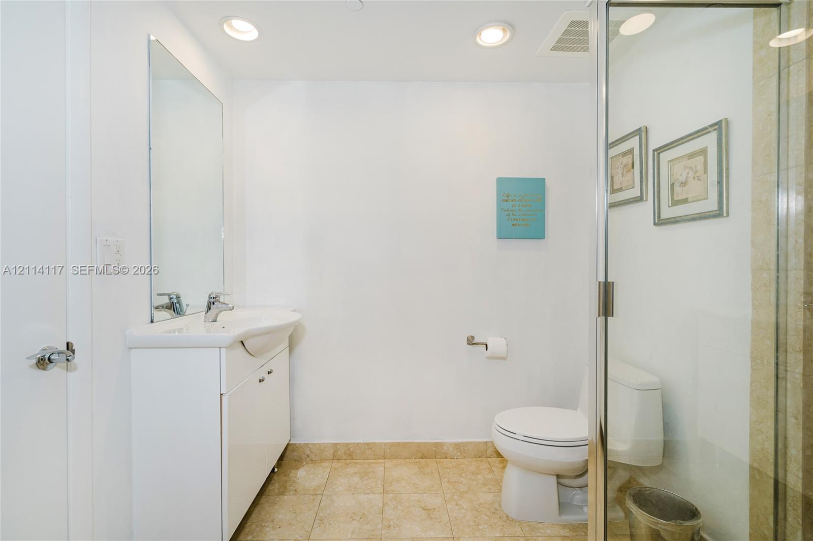 Bathroom featuring a vanity with an integrated sink and chrome faucet, frameless glass shower enclosure, recessed lighting, and tile flooring