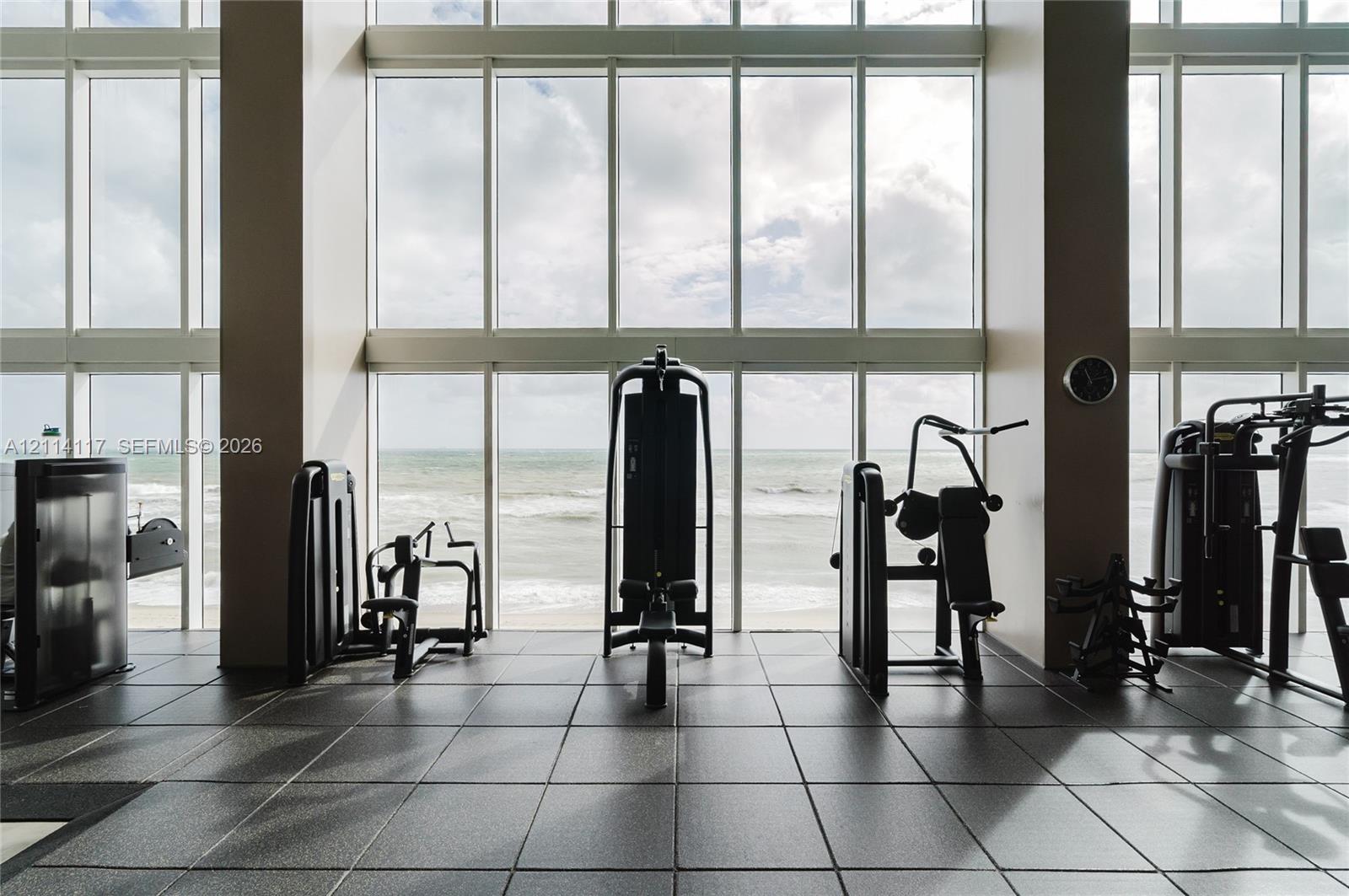 Floor-to-ceiling windows featuring ocean scenery, square tile flooring, and expansive structural columns