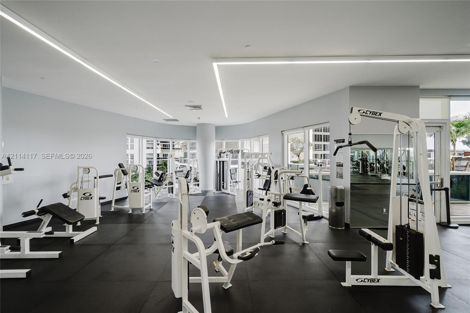 Fitness center featuring linear LED lighting, floor-to-ceiling windows, and impact-resistant rubber flooring