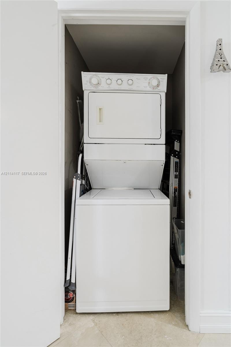 Stacked white laundry appliance set enclosed in a closet with neutral wall finishes