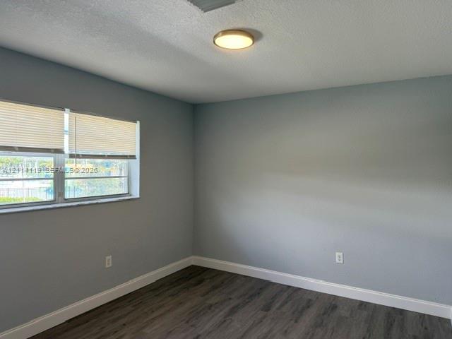 Neutral-toned walls featuring wood-finish flooring, a flush-mount circular light fixture, and horizontal window blinds