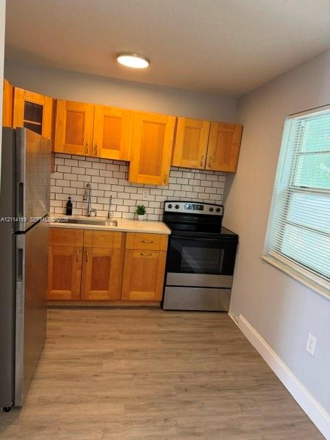 Kitchen featuring light-finish cabinetry, subway tile backsplash, stainless steel appliances, and wood-finish flooring