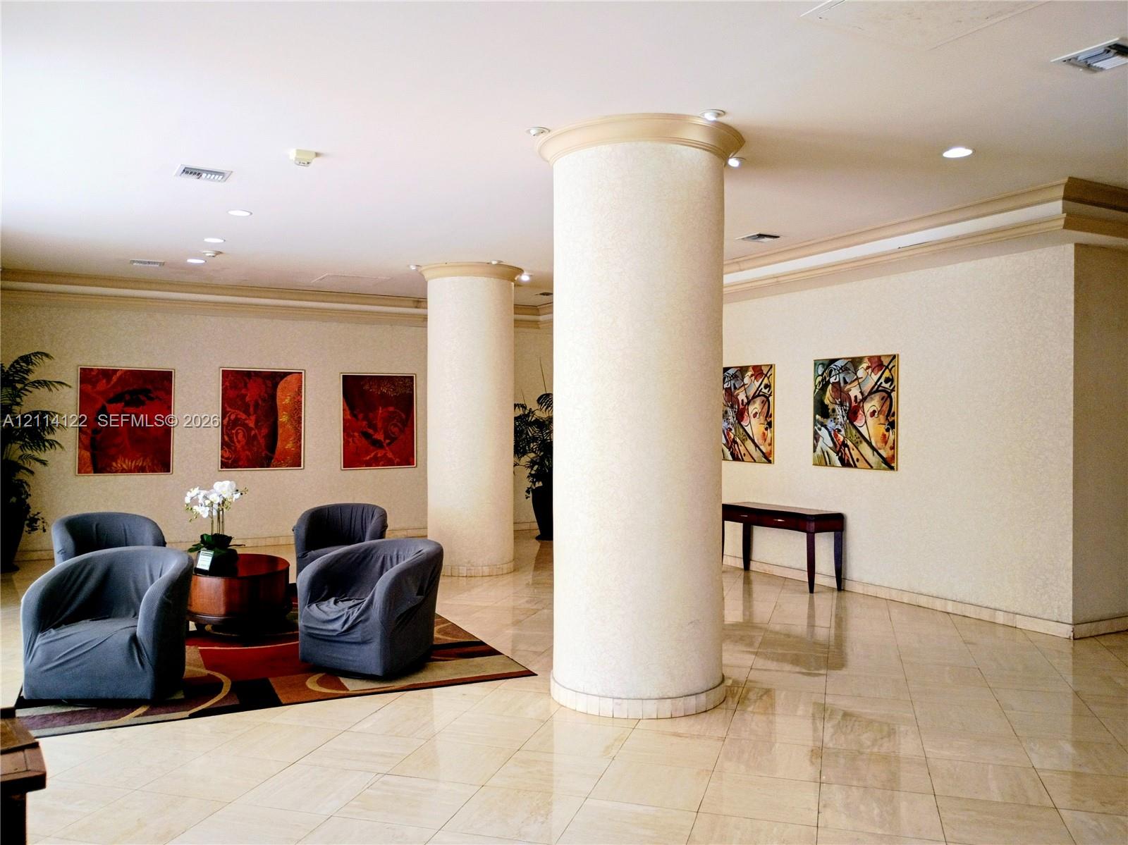 Interior lobby featuring light-toned stone flooring, recessed ceiling lighting, crown molding, and prominent cylindrical structural columns Interior lobby featuring light-toned stone flooring, recessed ceiling lighting, crown molding, and prominent cylindrical structural columns