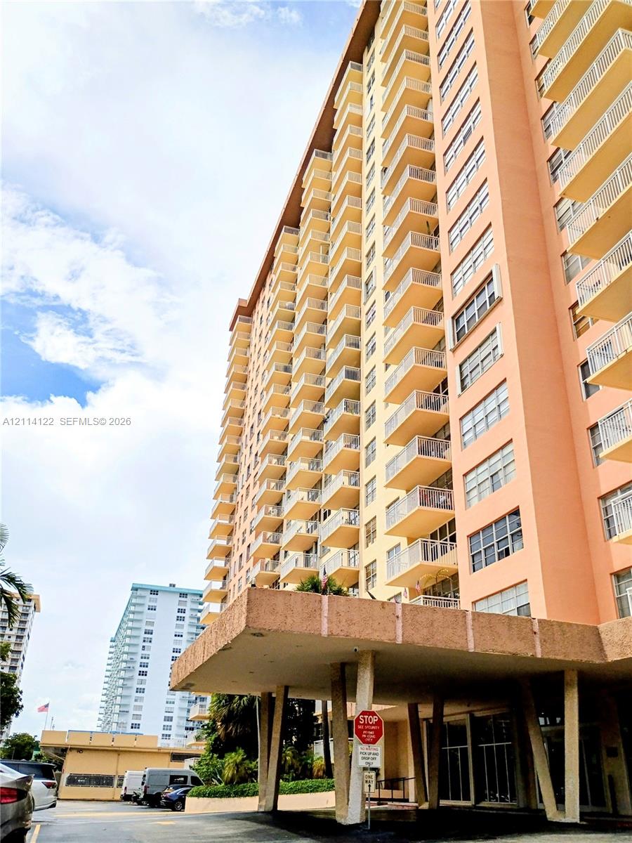 High-rise residential exterior featuring a covered porte-cochre with concrete structural supports and private balconies