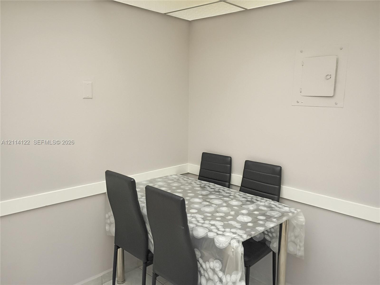 Neutral-toned interior space featuring light-colored wall finish, linear wall molding, and recessed ceiling grid panel Neutral-toned interior space featuring light-colored wall finish, linear wall molding, and recessed ceiling grid panel