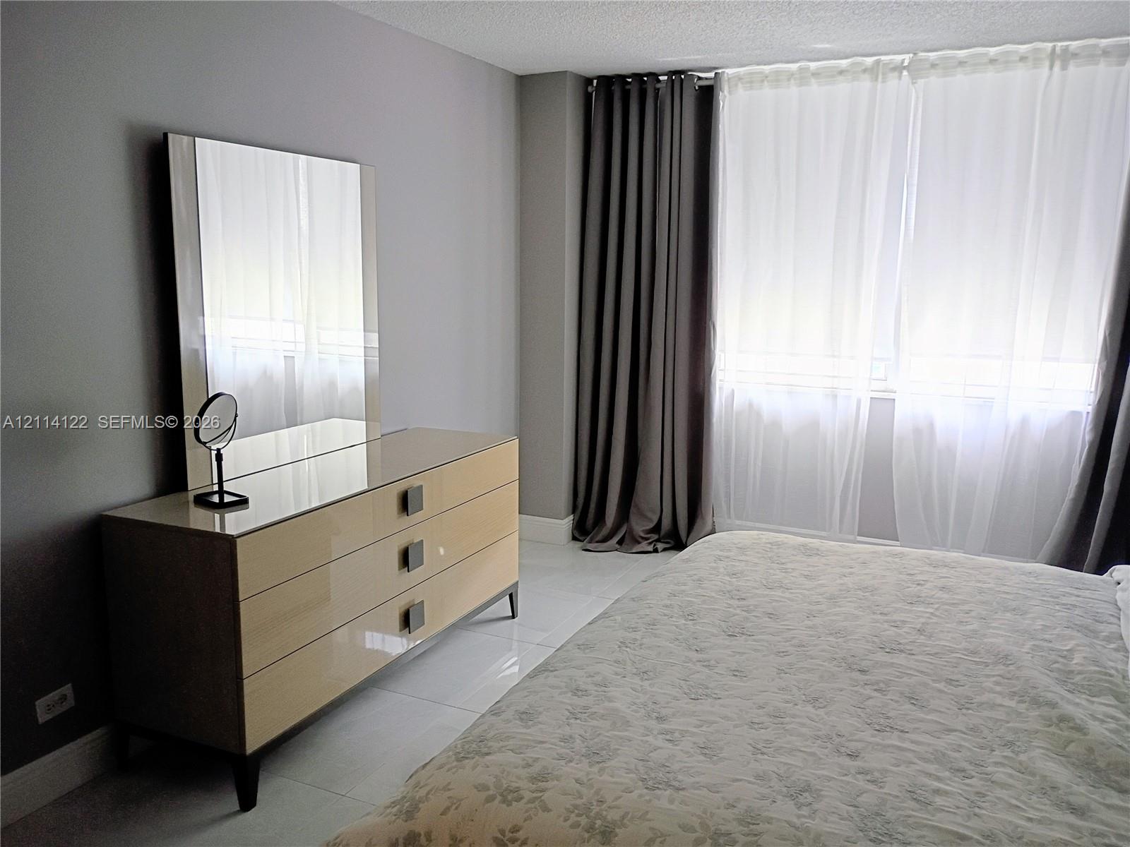 Neutral-toned wall finish, large-format tile flooring, and floor-to-ceiling window treatments