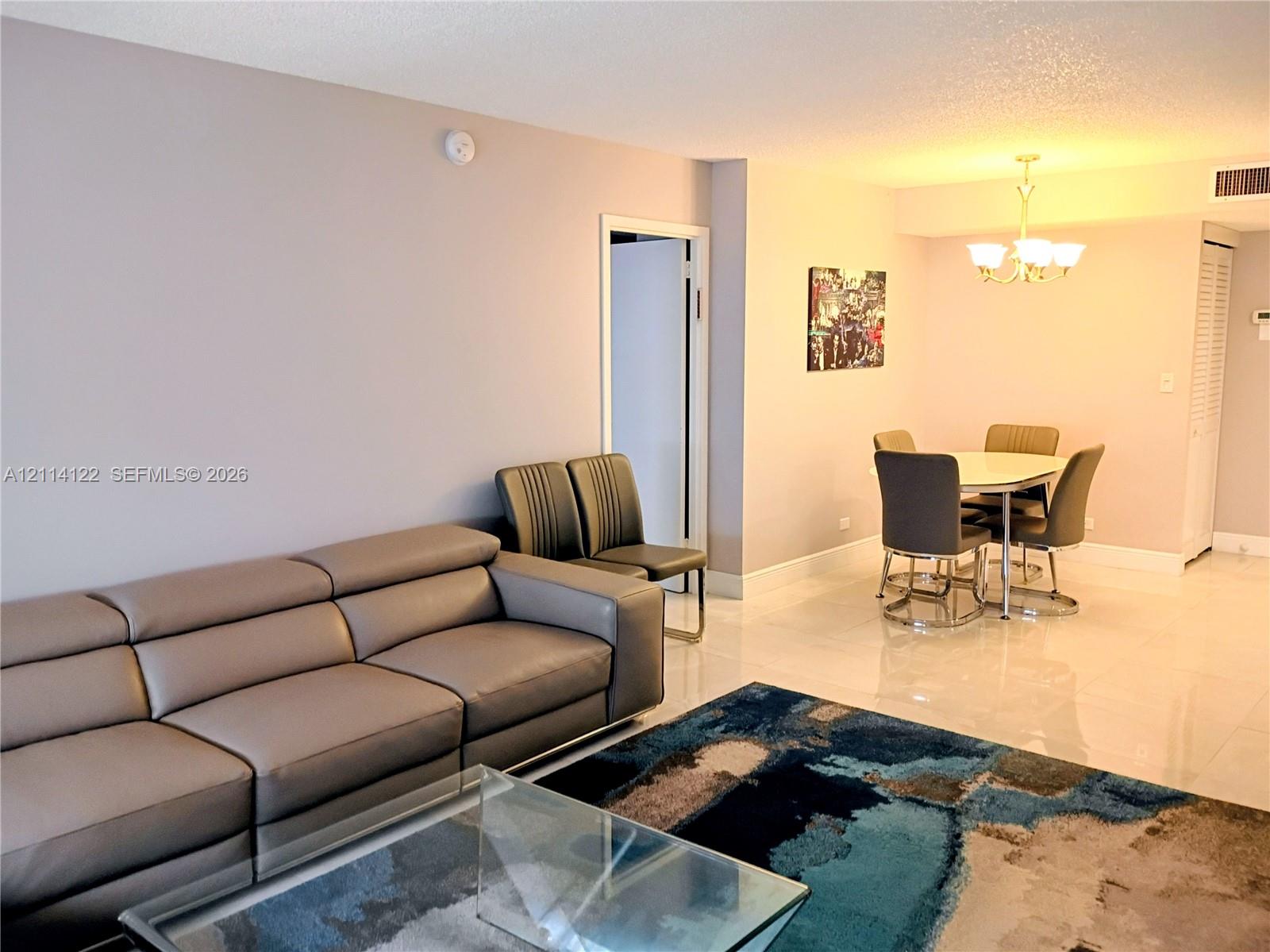 Polished tile flooring, neutral wall tones, and a multi-arm metallic chandelier