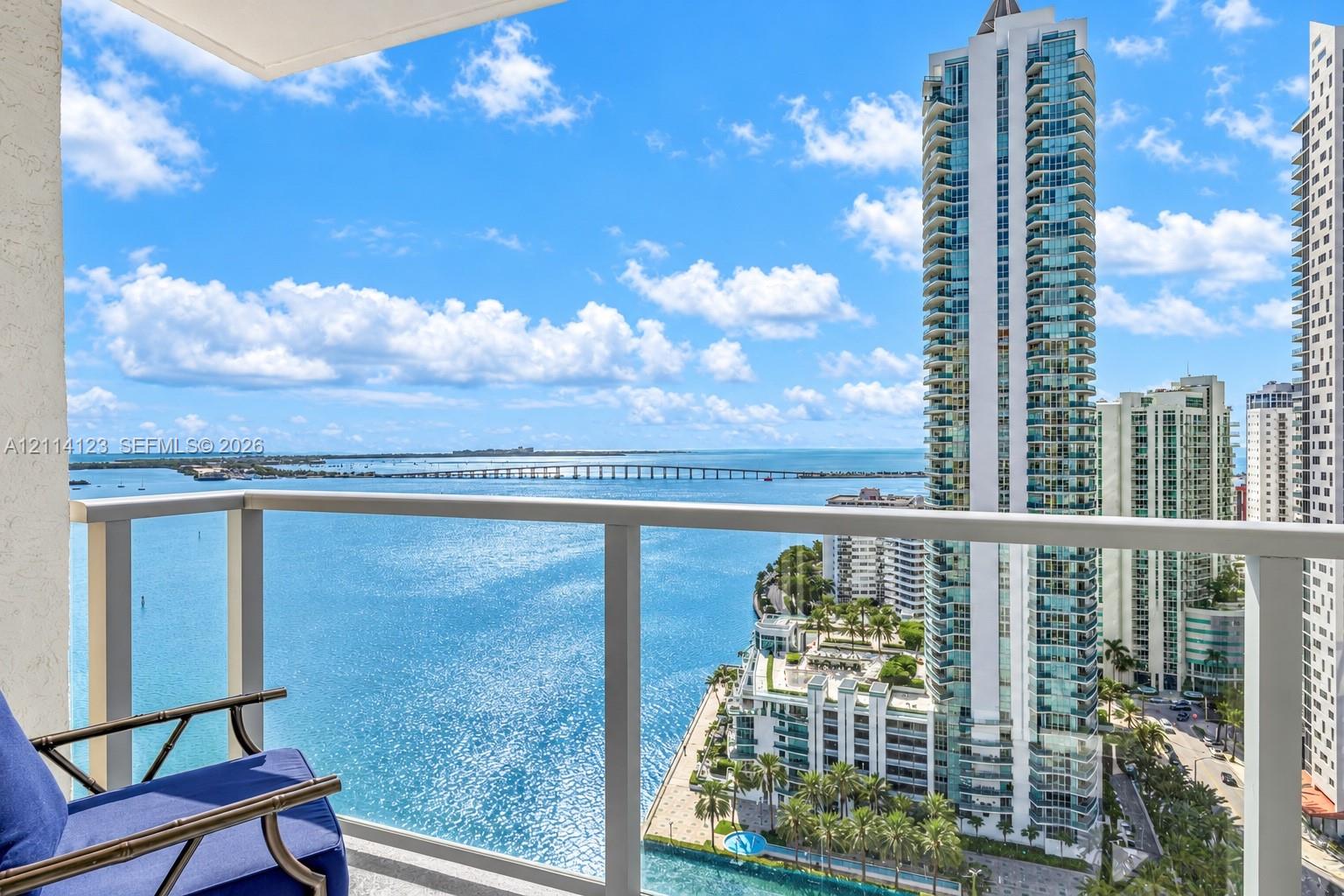 Private balcony featuring a glass-panel railing and open-air space with extensive water and urban skyline scenery Private balcony featuring a glass-panel railing and open-air space with extensive water and urban skyline scenery