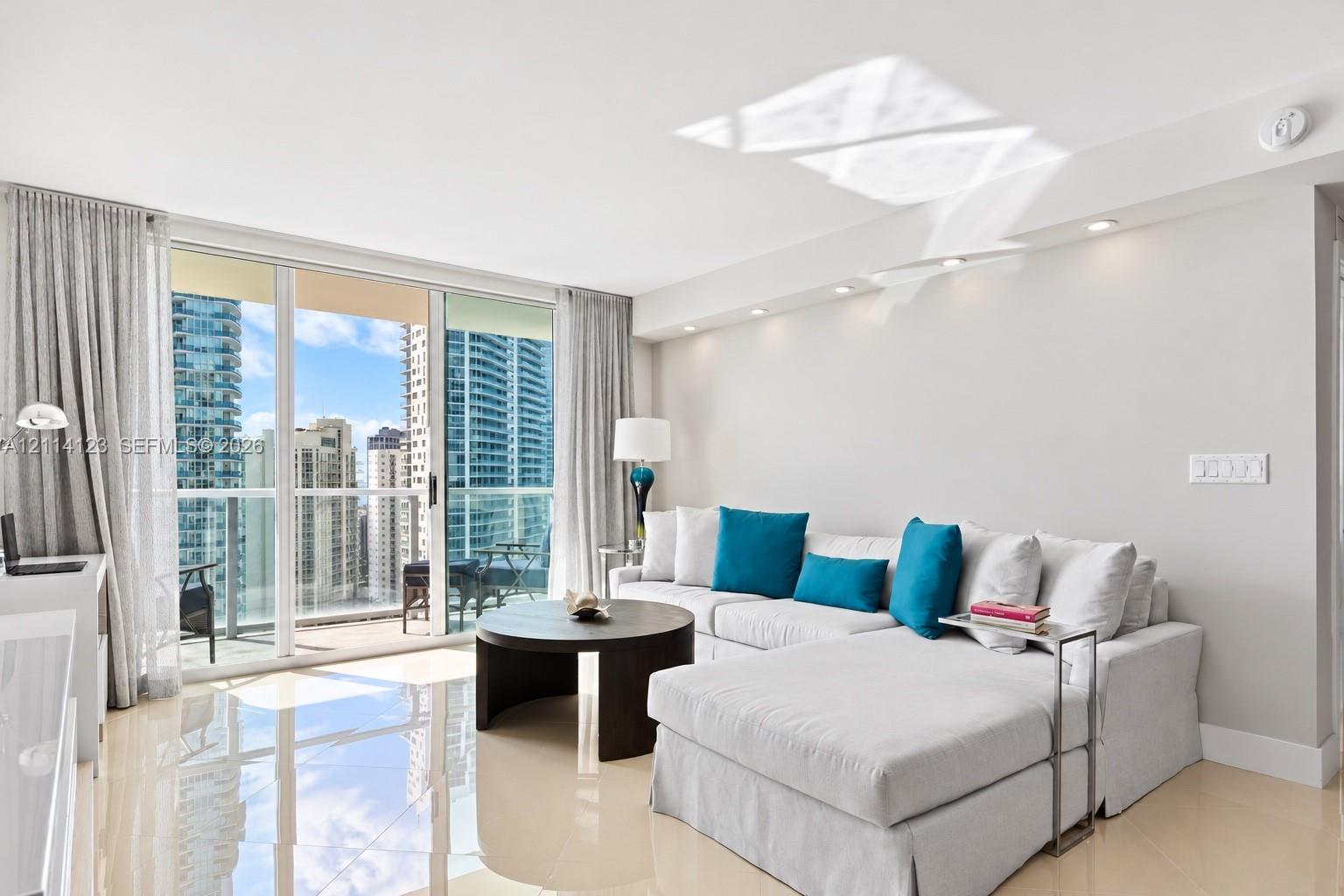 Floor-to-ceiling sliding glass doors, private balcony, polished tile flooring, and recessed ceiling lighting
