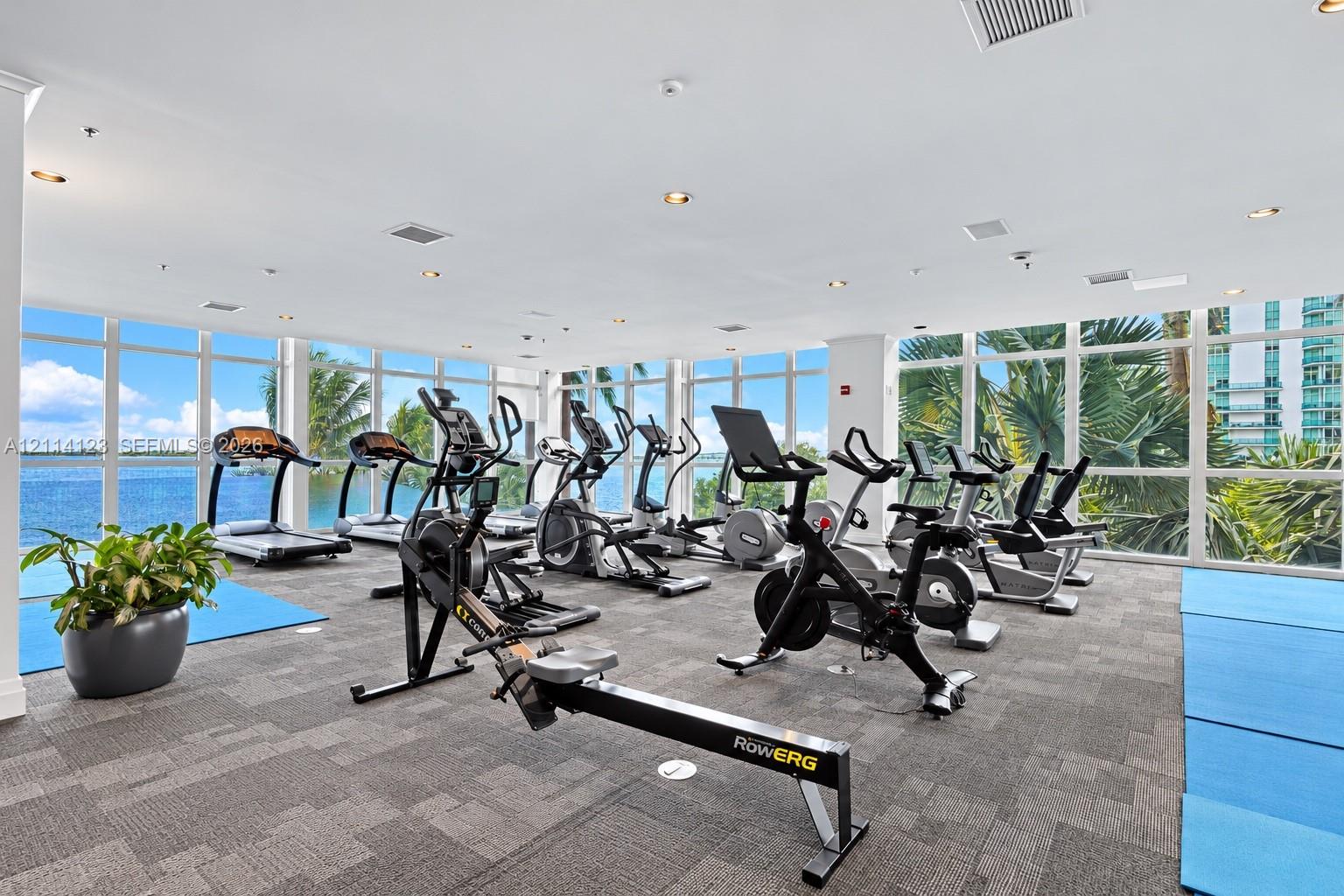 Fitness center featuring floor-to-ceiling windows, panoramic water exposure, recessed lighting, and carpeting