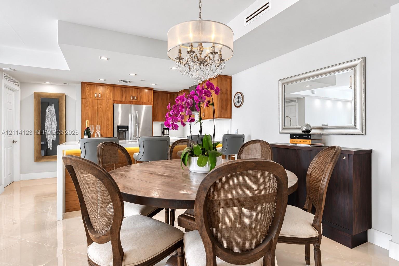 Dining area featuring polished tile flooring, a crystal chandelier, and a built-in kitchen peninsula with illuminated base cabinetry