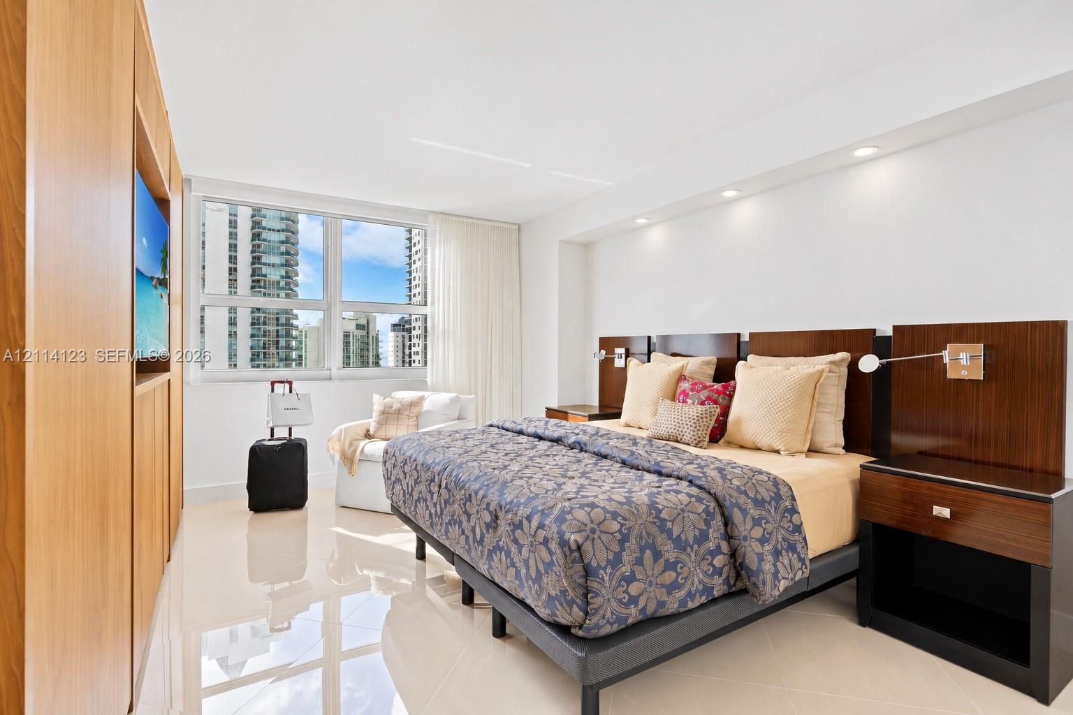Polished tile flooring, custom wood-finish built-in cabinetry, integrated recessed lighting, and wall-mounted reading lights