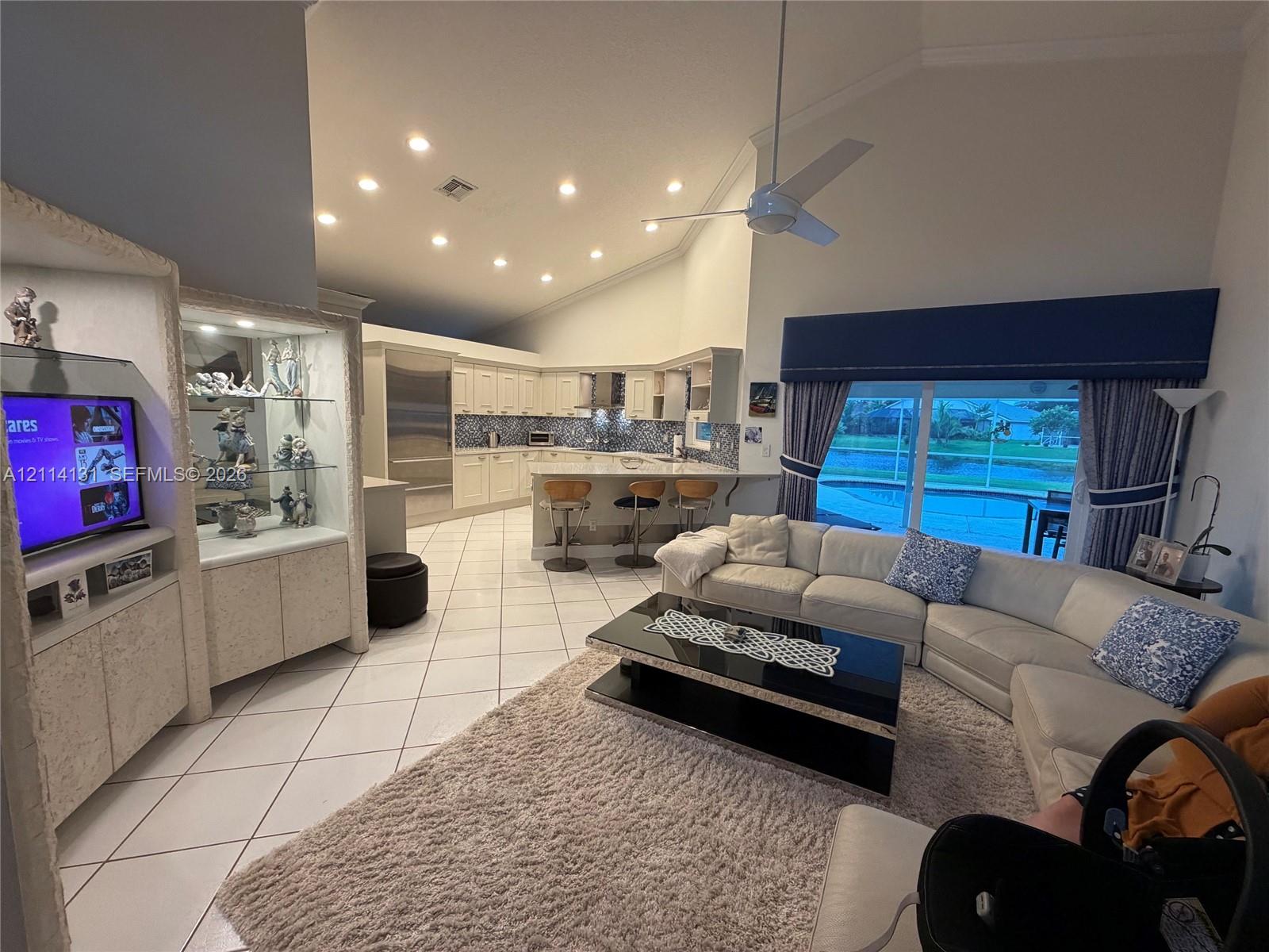 Vaulted ceilings with recessed lighting, tiled flooring, built-in display cabinetry, and a kitchen island with bar seating